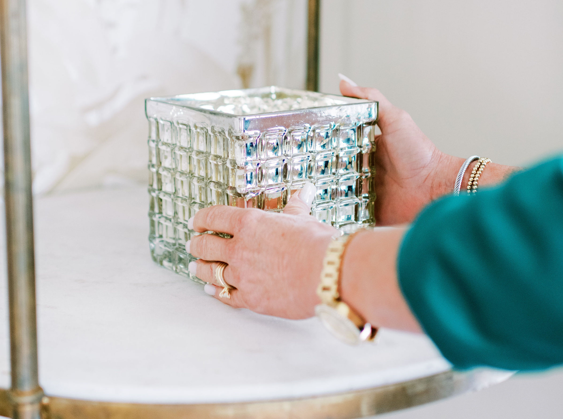 A woman's hand placing a silver metallic cube on a shelf